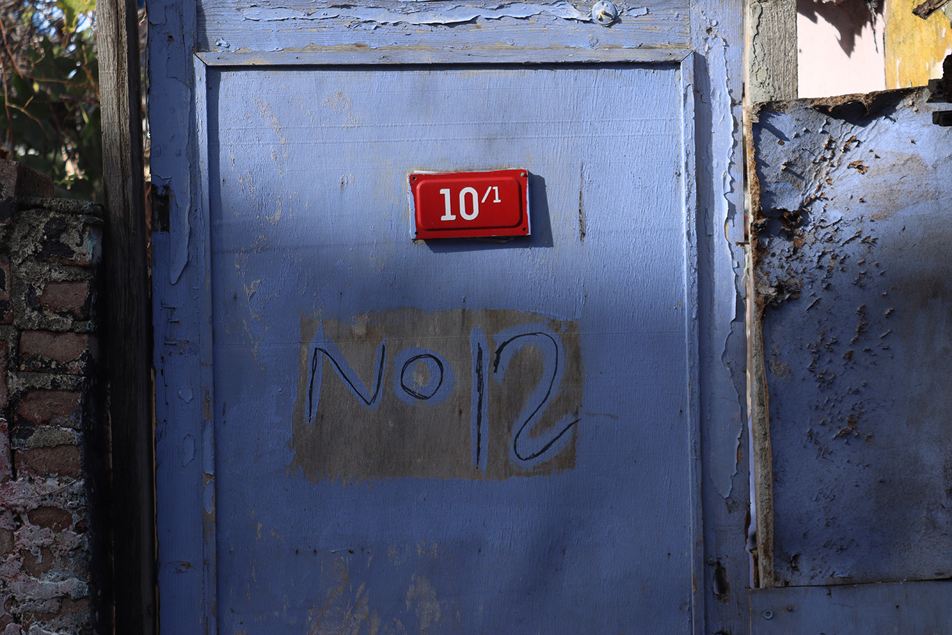 A light blue door with a sign that reads '10/1' but also has a hand written note that reads 'No 12'.