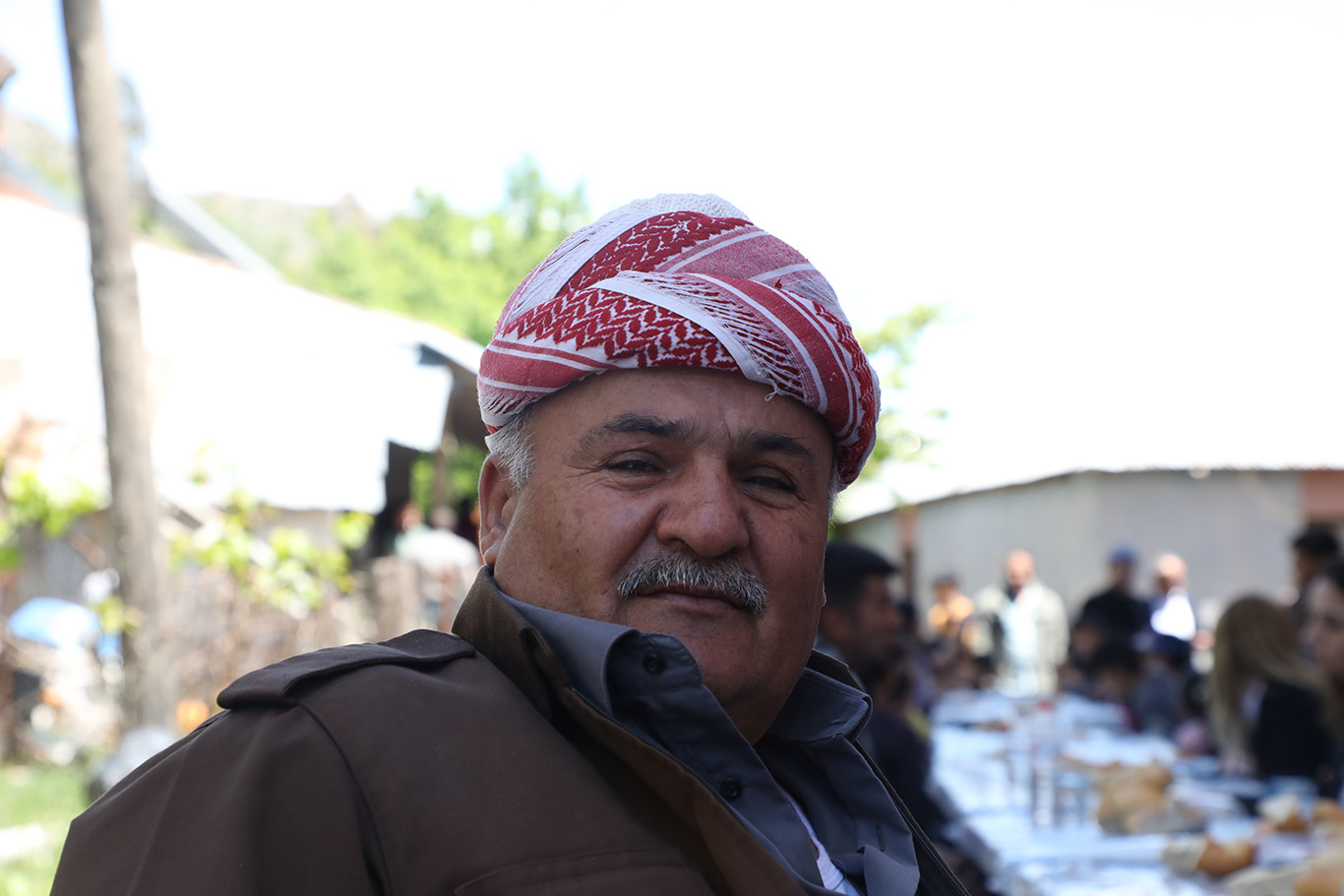 A smiling man wearing a red and white Iraqi traditional turban.