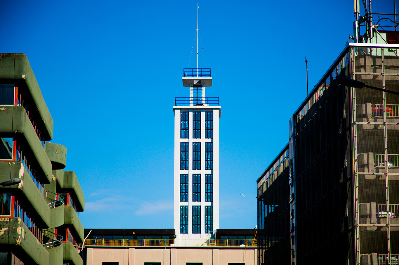 A tower surrounded by other buildings in front of the blue sky.