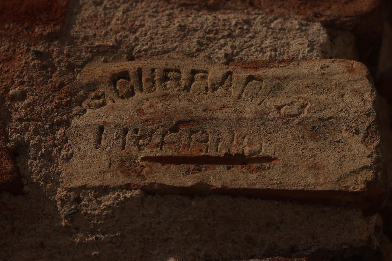 An unreadable writing carved in a beige stone wall.