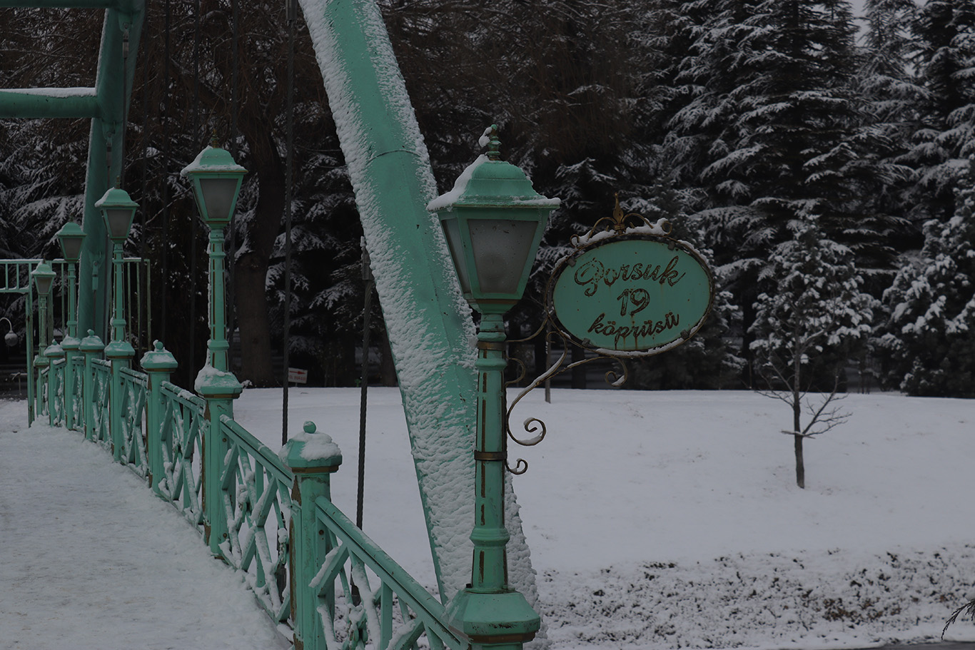 A green bridge covered in snow.